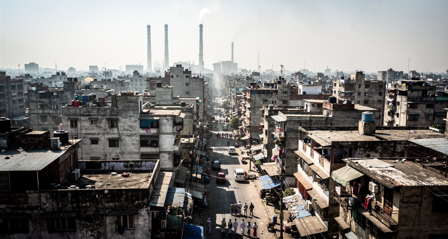 Dense South Asian city under intense midday heat with heat shimmer rising from concrete and asphalt streets