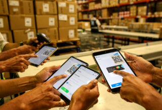 E-commerce fulfillment workers processing UPI payments on tablets in an Indian warehouse