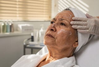 Elderly woman receiving facial treatment in Singapore beauty salon, clinical spa setting