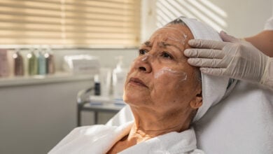 Elderly woman receiving facial treatment in Singapore beauty salon, clinical spa setting