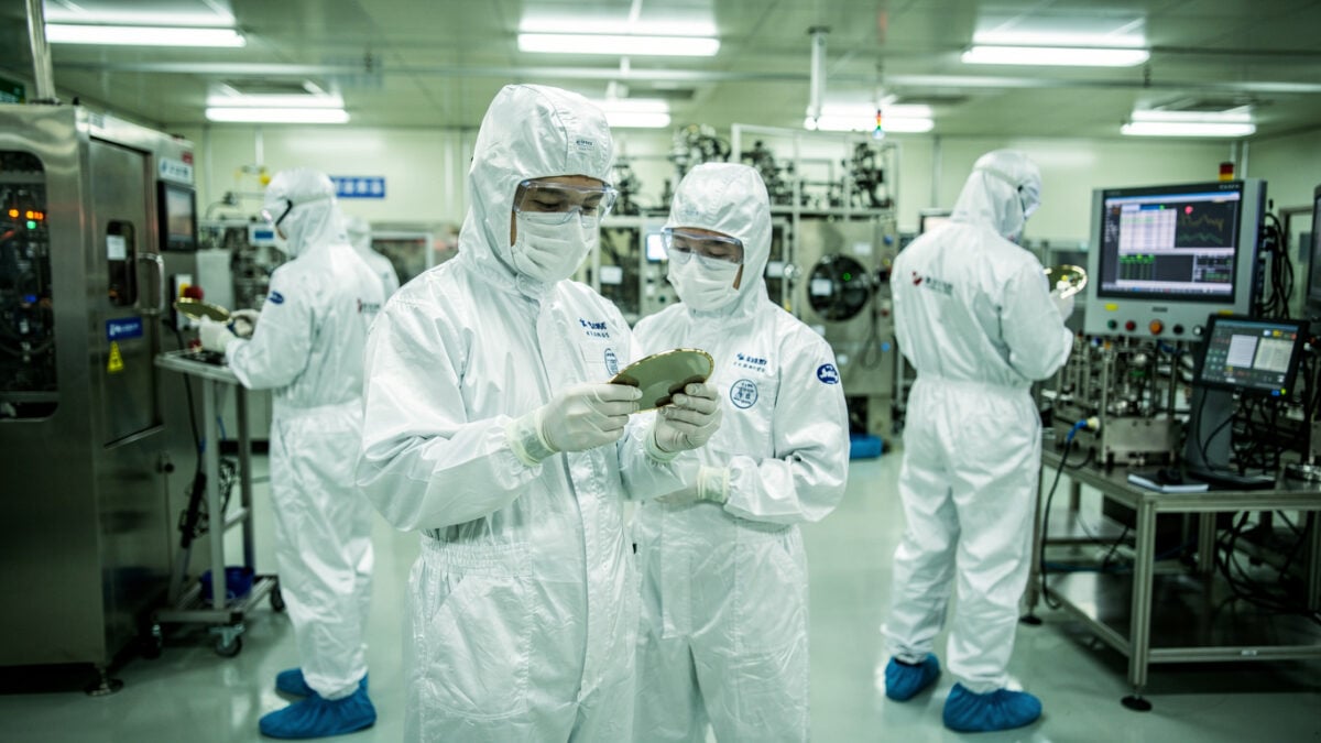 Engineers in cleanroom examining semiconductor wafers in Shanghai fab facility under bright industrial lighting