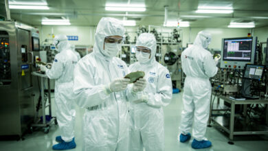 Engineers in cleanroom examining semiconductor wafers in Shanghai fab facility under bright industrial lighting