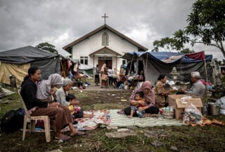 Families sheltering in churchyard on Flores after earthquake, tents and blankets visible