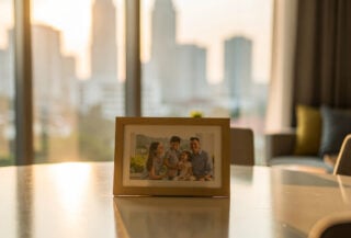 Family photograph on dining table in modern Kuala Lumpur condominium, morning light, urban skyline visible through windows