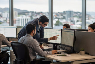 Finance team reviewing automated reconciliation data on monitors in Wellington office