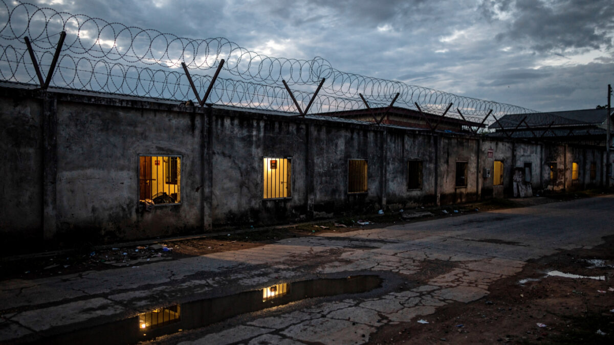 Guarded compound with barbed wire walls, Myanmar-Thailand border region, dusk lighting