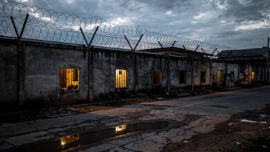 Guarded compound with barbed wire walls, Myanmar-Thailand border region, dusk lighting