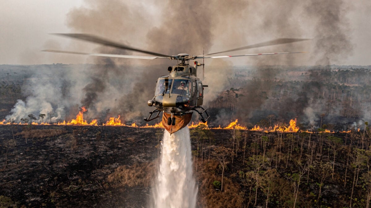 Helicopter conducting water-bombing run over burning peatland in Kalimantan, smoke and flames visible below