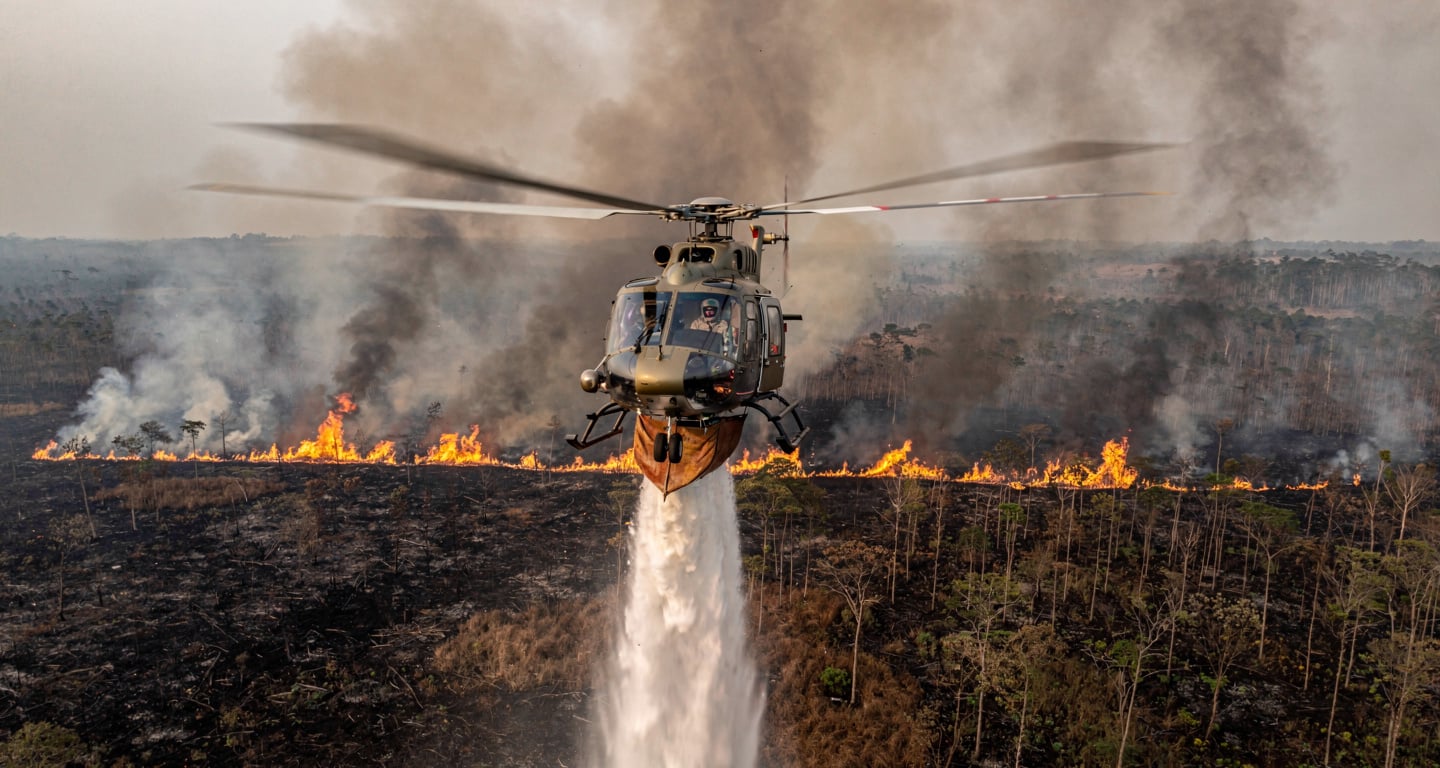 Helicopter conducting water-bombing run over burning peatland in Kalimantan, smoke and flames visible below
