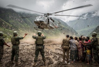 Rescue helicopter landing near Bidur with military personnel and waiting families in Himalayan valley