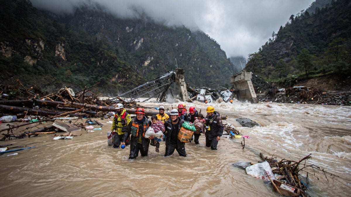 Rescue workers moving through debris-laden floodwaters in Nepal Himalayan valley after glacier collapse
