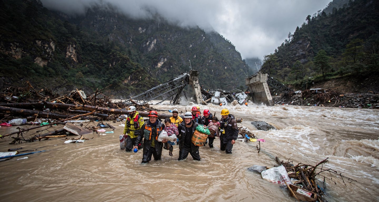 Rescue workers moving through debris-laden floodwaters in Nepal Himalayan valley after glacier collapse