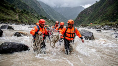 Rescue workers hauling equipment through flooded Himalayan river valley in Rasuwa district, Nepal