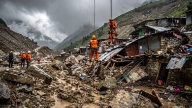 Rescue workers rappelling down debris-scarred Himalayan valley searching destroyed homes after glacier flood