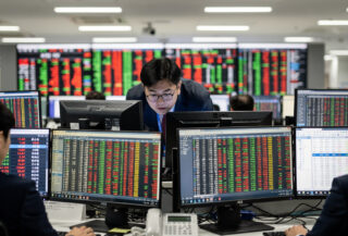 Seoul traders watching stock tickers spike on screens, dealing room, overhead lighting
