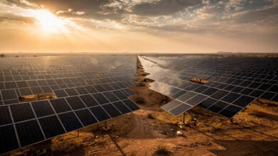 Solar panel array in Rajasthan, India under partly cloudy sky at midday