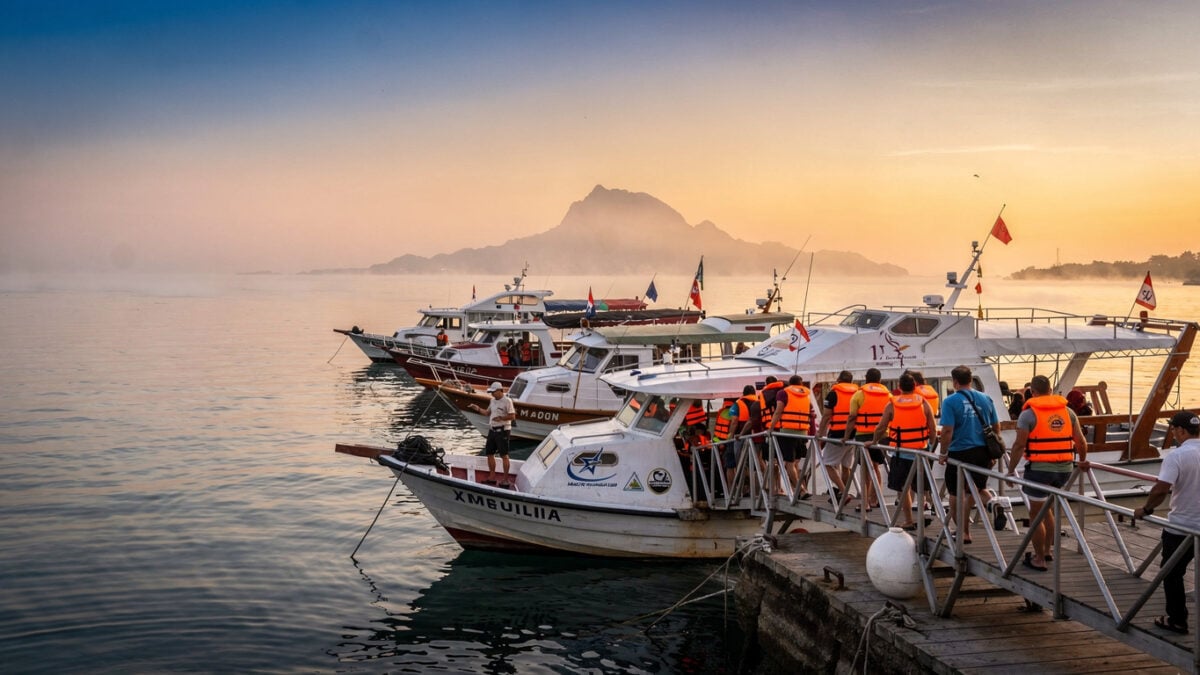 Tourist boats loading passengers at Marina Labuan Bajo, Komodo island in background, dawn light