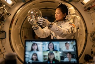 Astronaut conducting microgravity experiment inside Tiangong space station module during live classroom broadcast