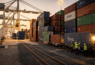 Cargo containers and cranes at Abu Dhabi eastern port facility during dawn operations with Etihad Rail loading