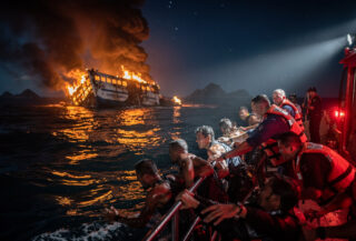 Coast Guard rescue boat pulling survivors from water near burning ferry, Coron Palawan, night