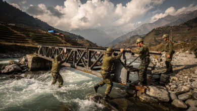 Nepali Army engineers assembling Bailey bridge across flooded mountain river, Nuwakot district, afternoon light