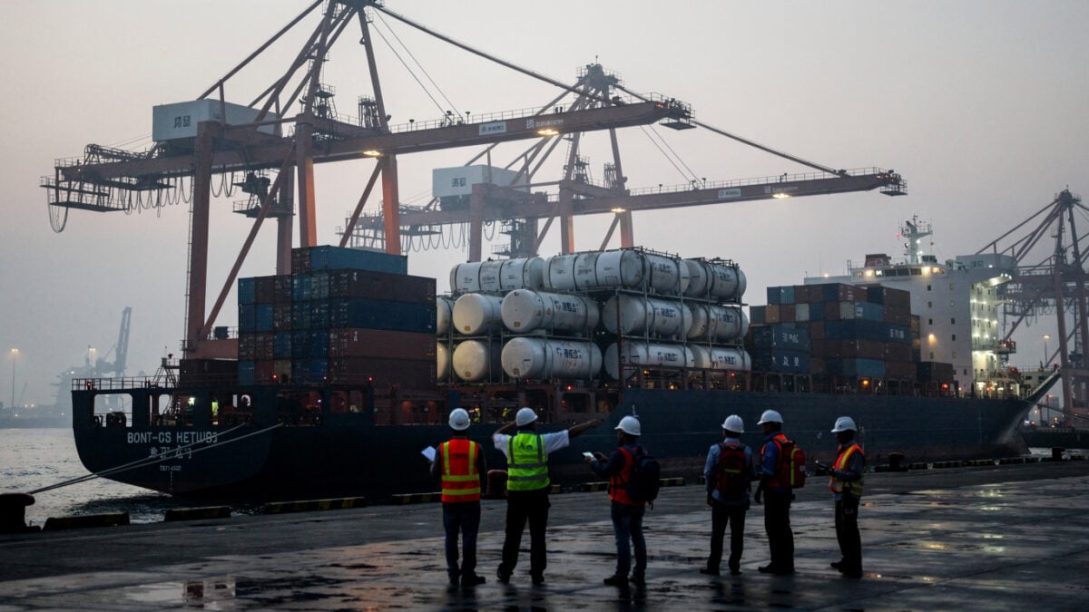 Oil tanker cargo at Chinese port terminal with dock workers and cranes, dawn light