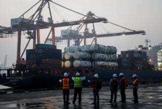 Oil tanker cargo at Chinese port terminal with dock workers and cranes, dawn light