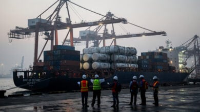 Oil tanker cargo at Chinese port terminal with dock workers and cranes, dawn light