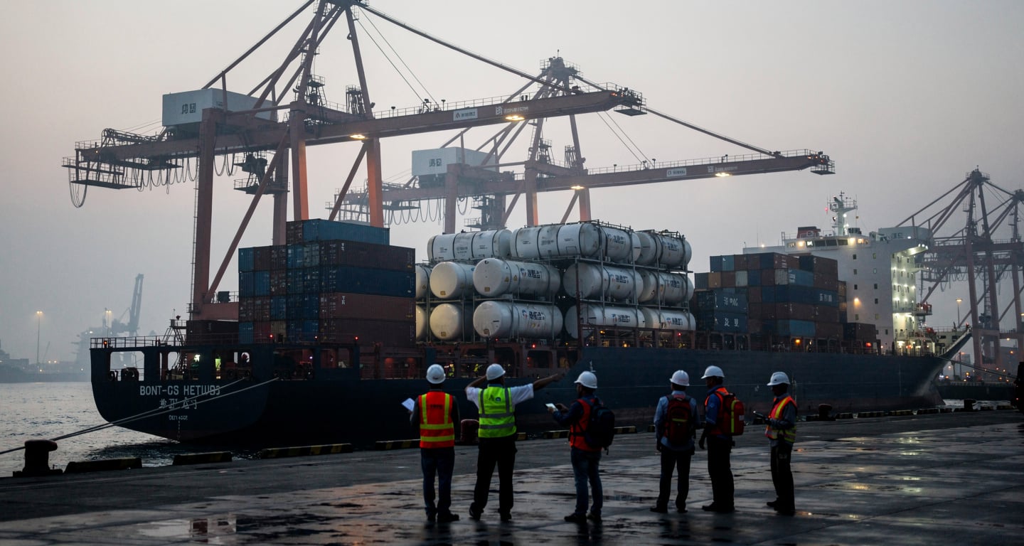 Oil tanker cargo at Chinese port terminal with dock workers and cranes, dawn light