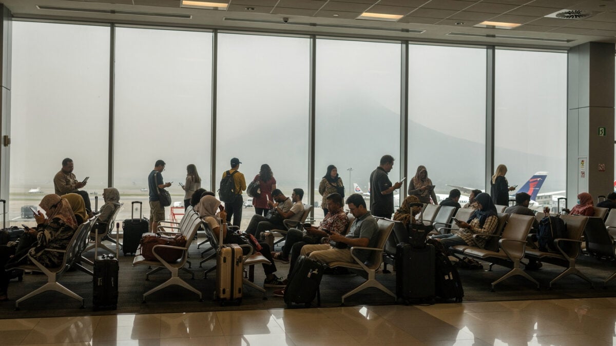 Passengers at Jakarta airport departure gates with ash-hazed windows during volcanic closure