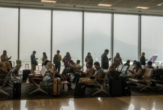 Passengers at Jakarta airport departure gates with ash-hazed windows during volcanic closure