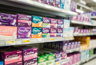 Period-care product shelf in Australian supermarket displaying Carefree, Stayfree, and competing brands under fluorescent lighting