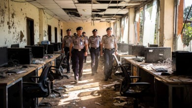 Police officers inspecting abandoned scam compound in Phnom Penh, empty desks and computers visible