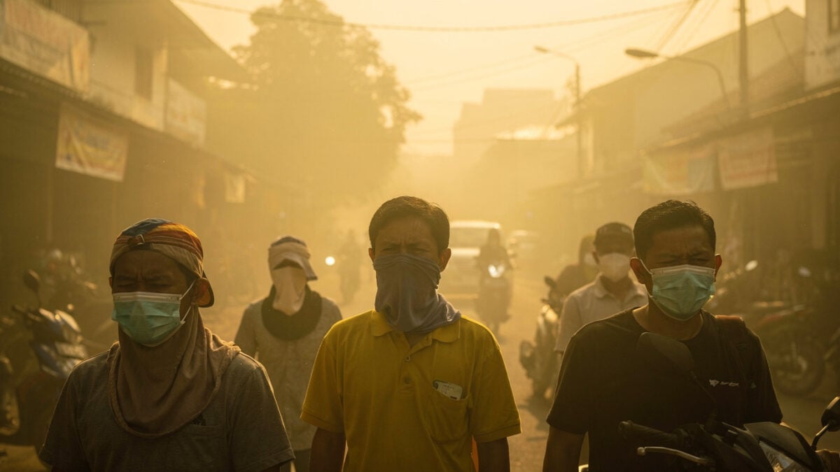 Pontianak residents wearing masks against thick yellow smoke haze on street, midday