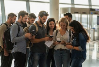 Travelers reviewing documents at Dubai airport departure hall amid travel advisory uncertainty
