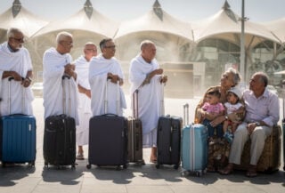 Elderly pilgrims waiting with suitcases outside Jeddah Hajj Terminal