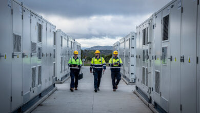 Technicians walking between battery units at NSW's Waratah site