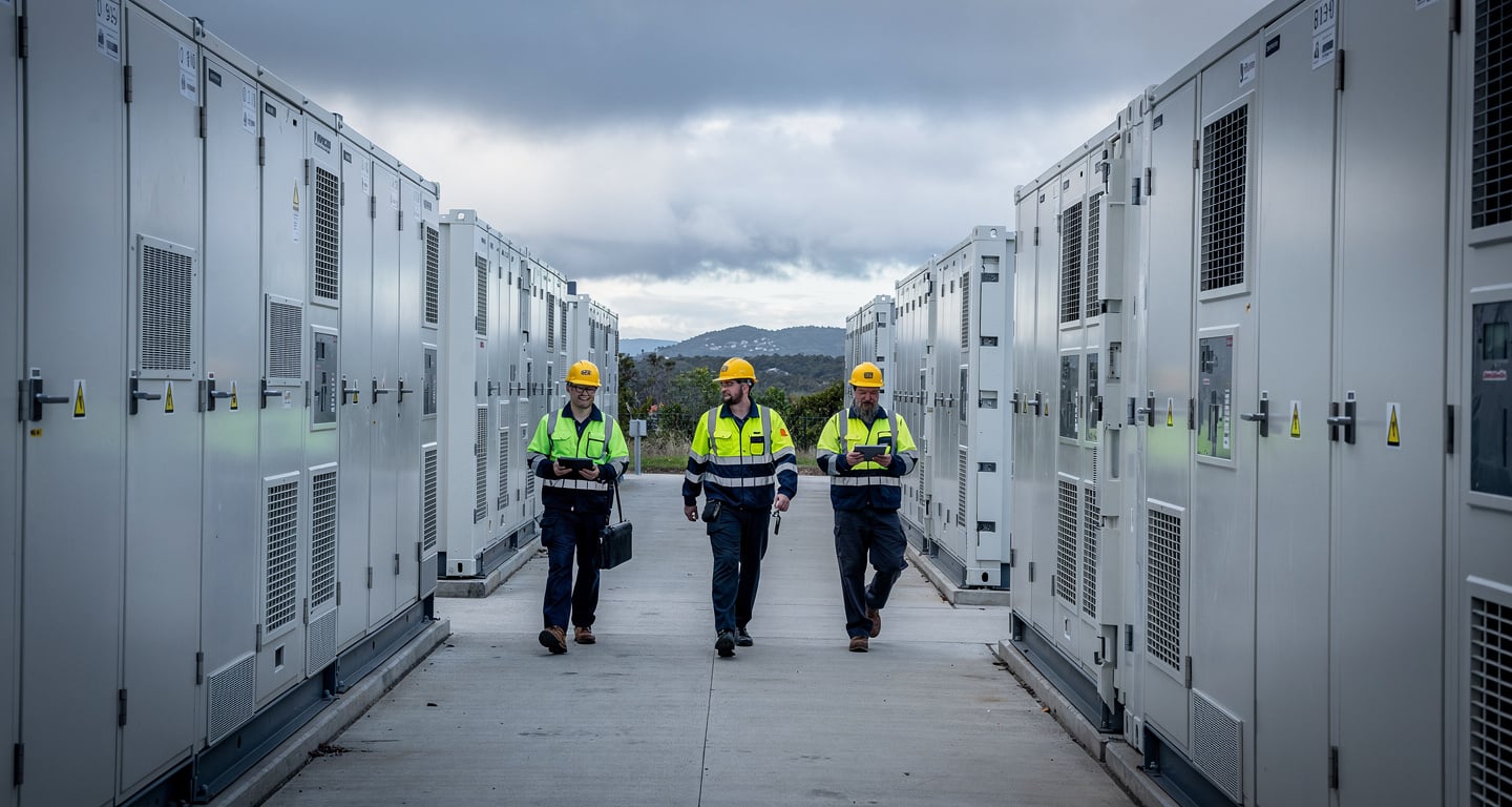 Technicians walking between battery units at NSW's Waratah site